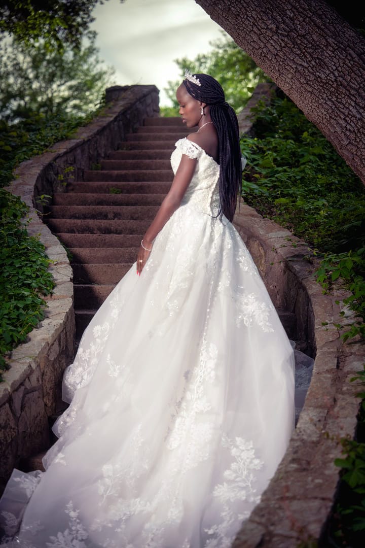 Bride poses for photo in dress outside on winding stairs.