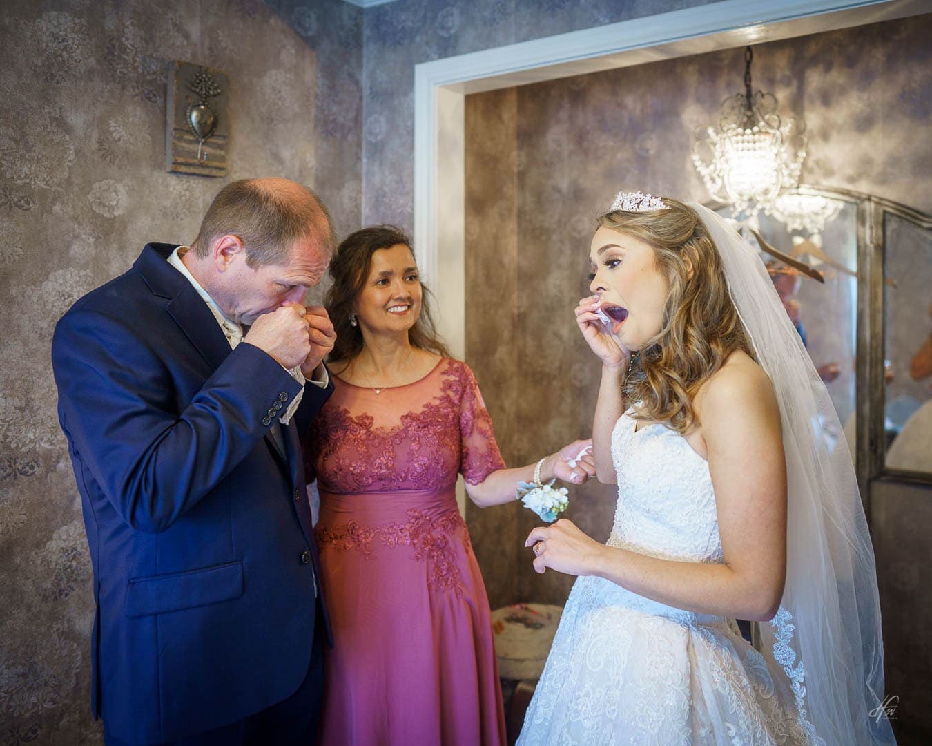 Father and bride wipe away tears. Mom smiles.
