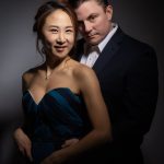 Couple posing for portrait in dark studio.
