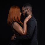 Couple posing for portrait in dark studio.