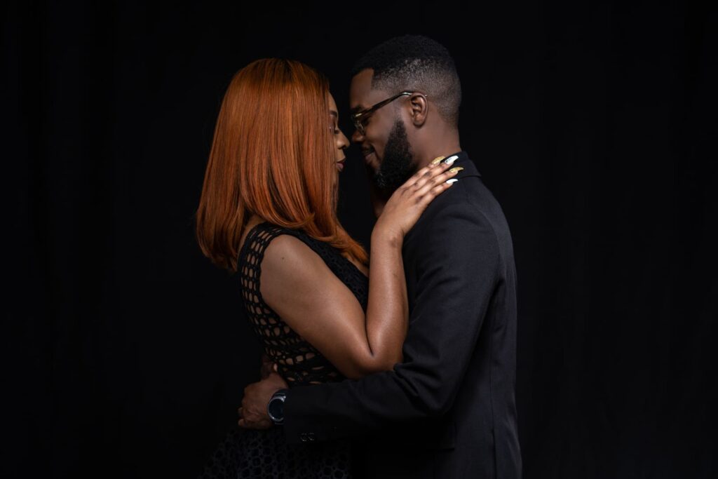 Couple posing for portrait in dark studio.