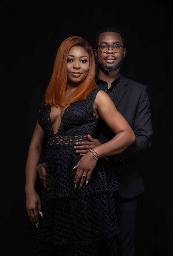 Couple posing for portrait in dark studio.
