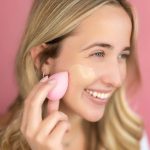 Girl applying cosmetics to cheek.