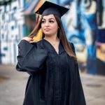 Girl poses for portrait. Wearing cap and gown.