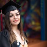 Girl poses for portrait. Wearing cap and gown.