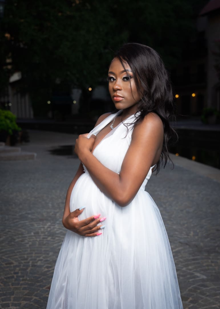Maternity photo of woman in white dress outside.