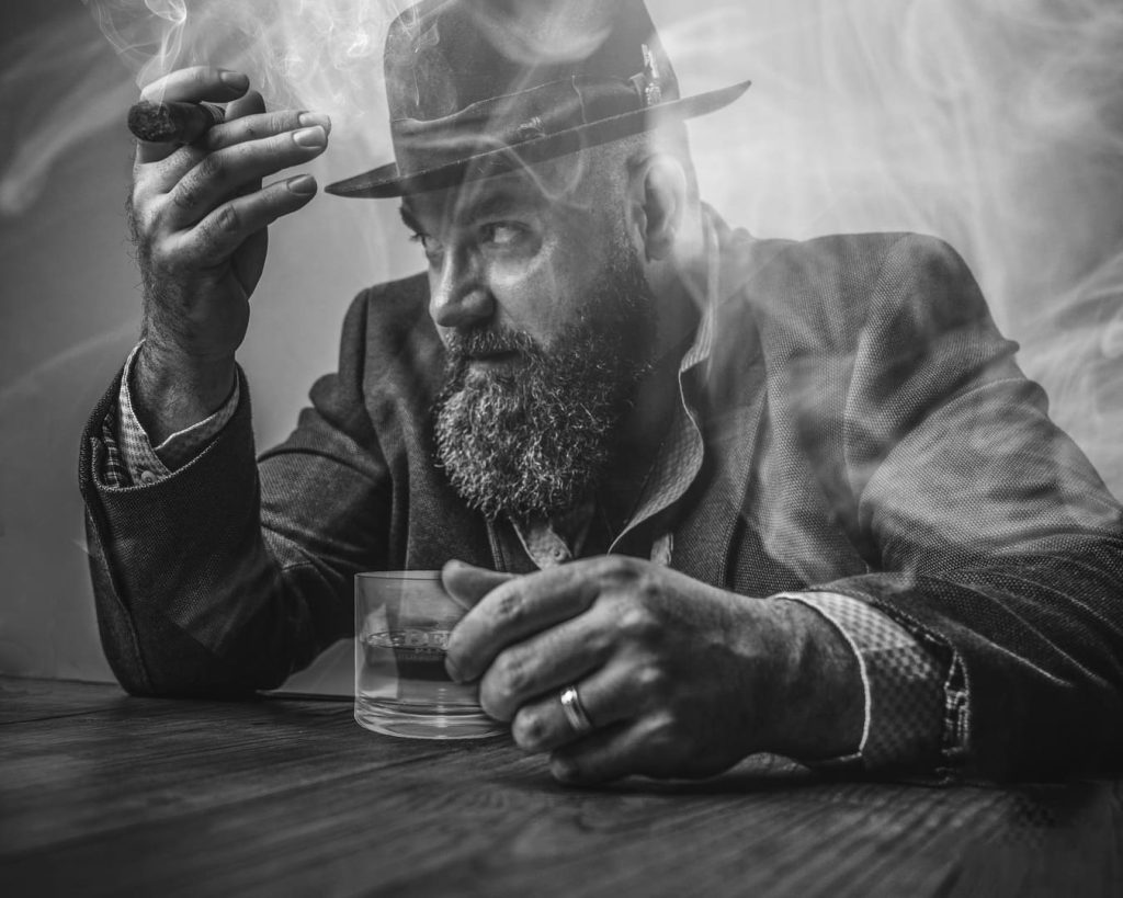 Man sitting at the bar smoking a cigar and having a drink.