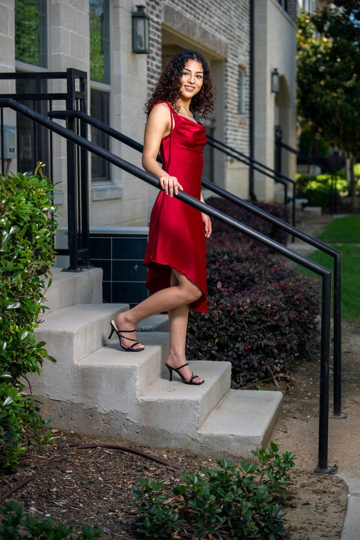 Girl walks down steps in red dress.