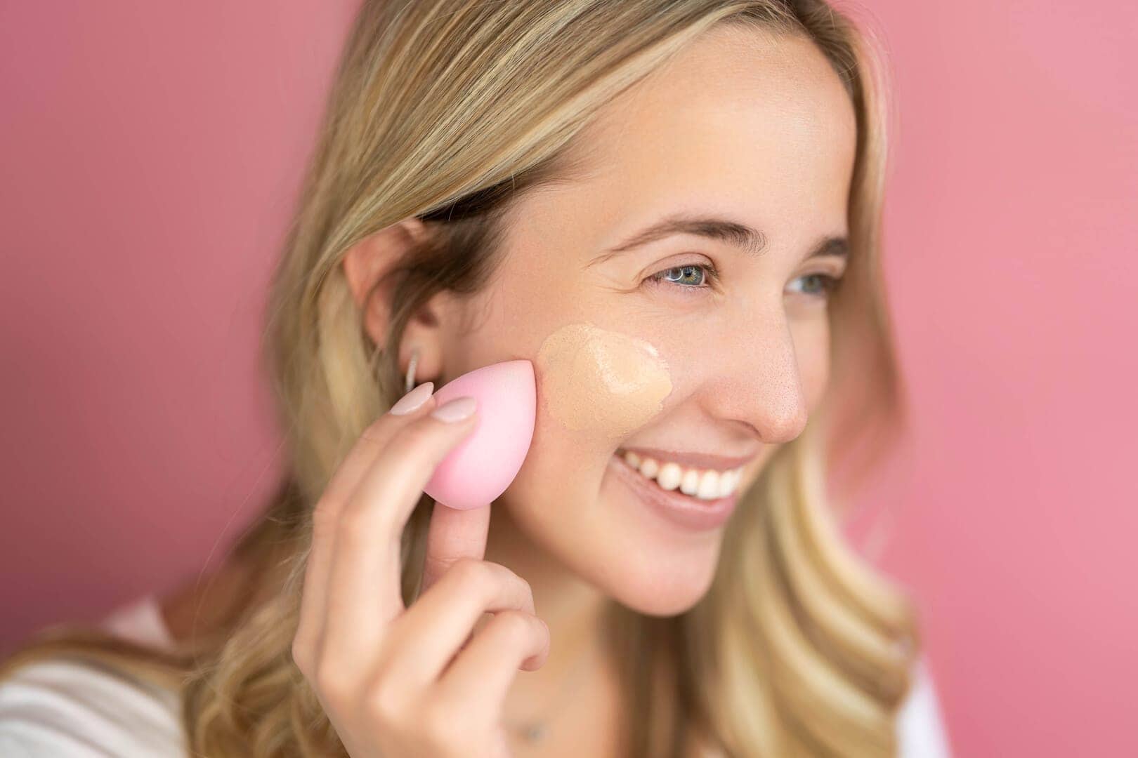 Girl applying cosmetics to cheek.