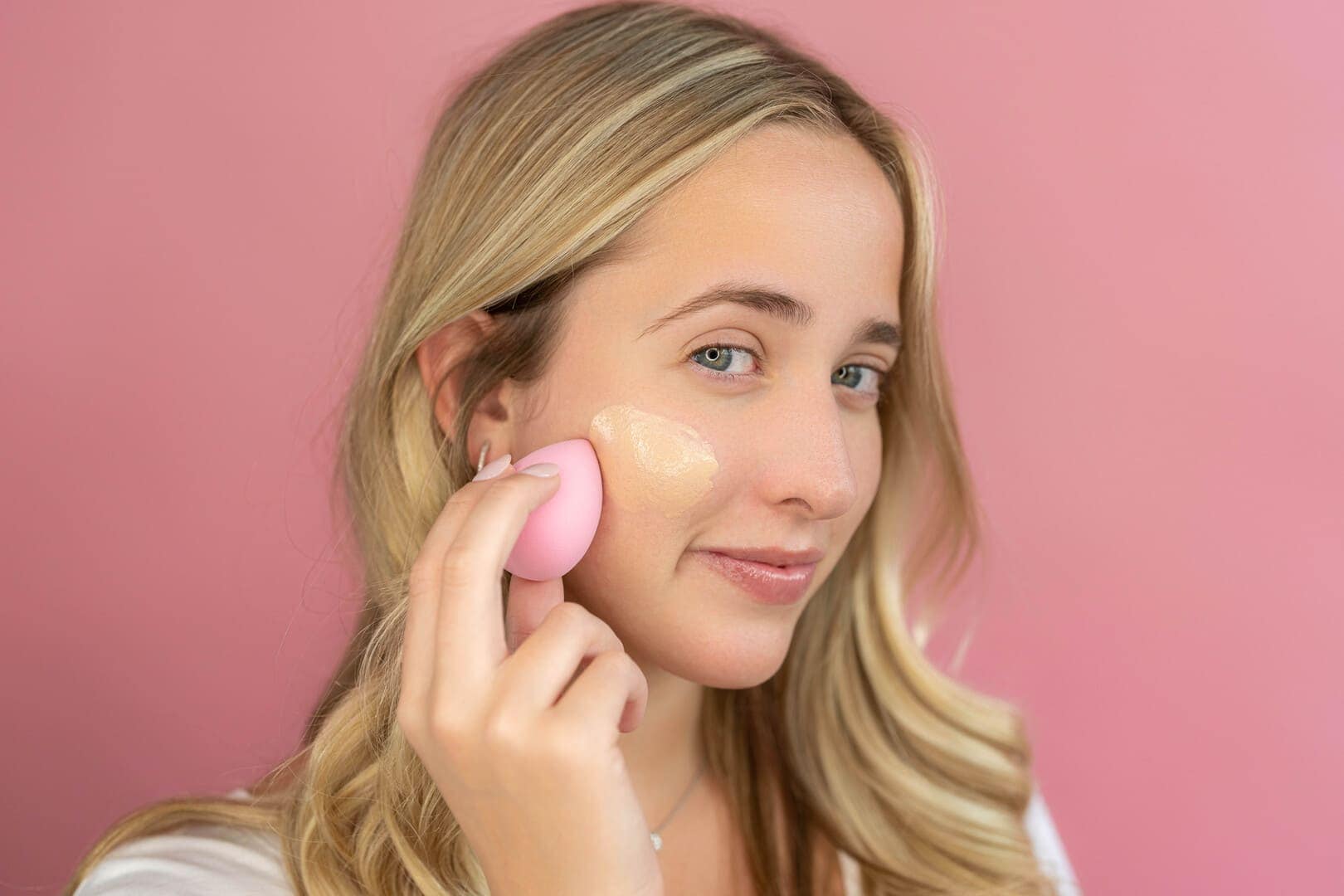 Girl applying foundation to cheek.