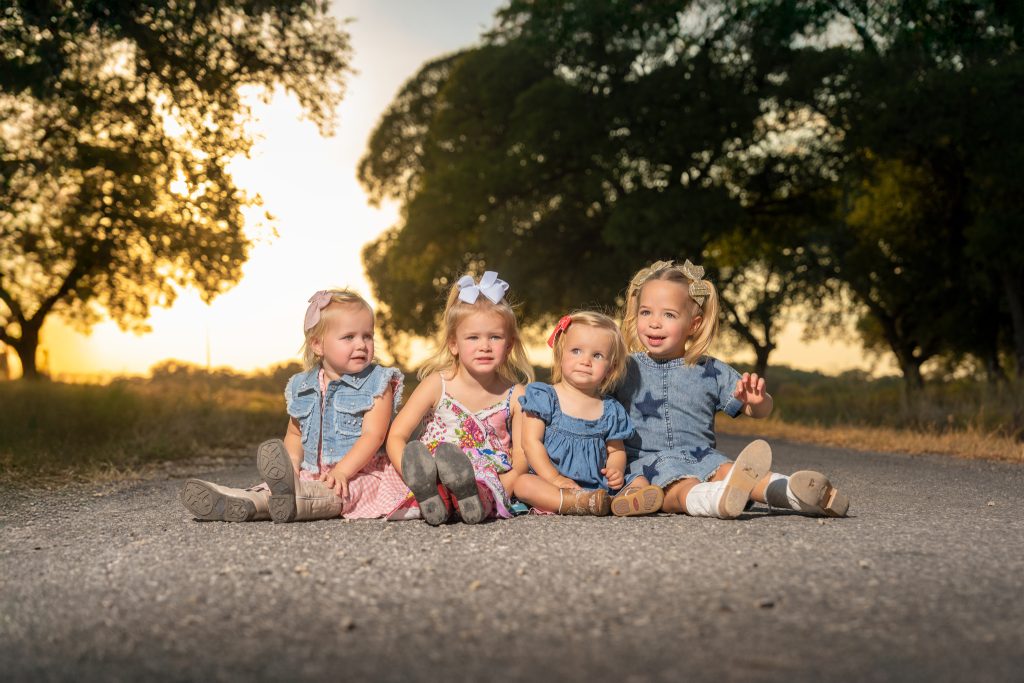 For little girls sitting in the road with the sun setting behind them.