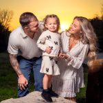 Proud parents looking at child at sunset.