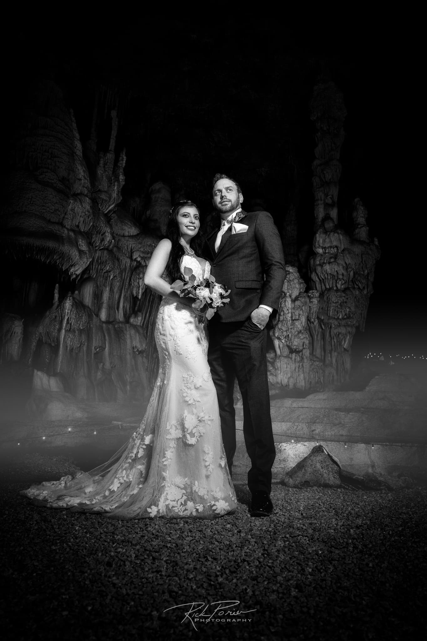 Bride and groom posing for portrait in a cave.